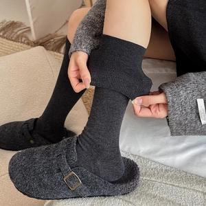 Close-up of elastic dark grey ribbed cotton socks with cozy felt wool-lined buckle shoes