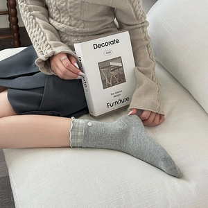 Detail of grey knit socks with plaid ruffle trim and small white flower accent