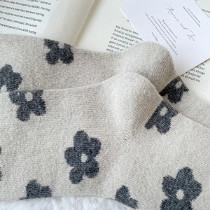 Detailed view of gray floral knit wool socks with vintage patterns on soft white fur