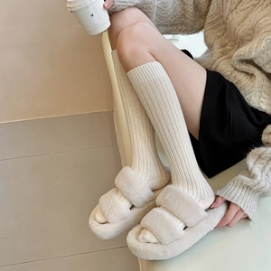 Close-up of ribbed knit knee high socks with plush triple-strap faux fur slippers