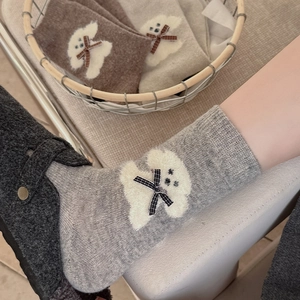 Close-up of knitted wool socks featuring plush puppy detail and plaid bow accents