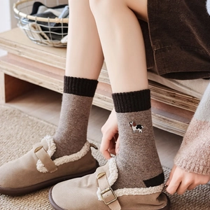 Detail of dog embroidery on thermal color-block wool socks worn with plush slippers