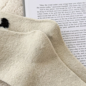 Macro detail of knit wool socks with 3D fuzzy pom-poms on cozy cream texture