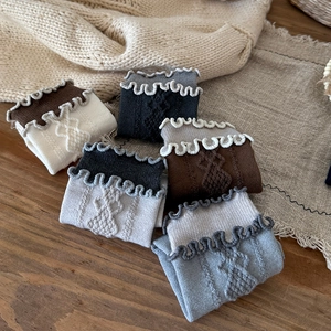 Close-up of vintage knit wool socks with ruffle cuffs and cable pattern in earthy tones