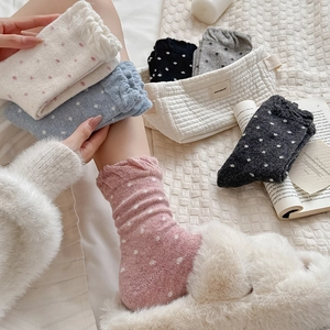 Detailed view of knitted polka dot crew socks with feminine ruffled cuffs in soft pastel tones