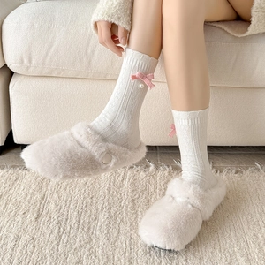 Sweet wool socks with pink bows and pearls paired with plush beige slippers for winter