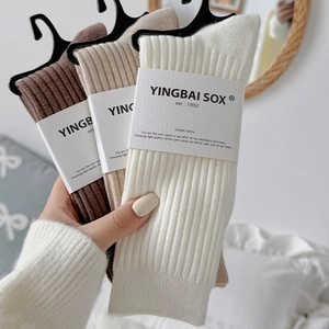 Detail of warm coffee-toned slouch socks with rib-knit texture and elegant packaging