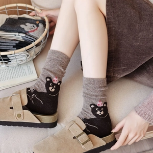 Detail of knitted ribbed socks featuring a cute cartoon bear embroidery in a cozy home setting