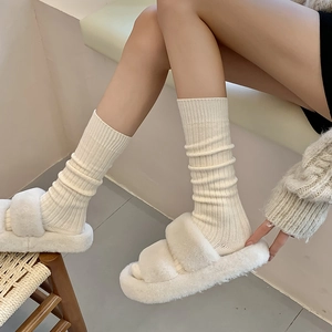 Detail of cream rib-knit knee-high socks paired with matching plush platform slippers