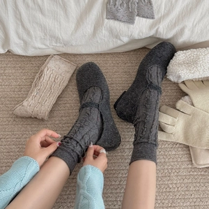Texture détaillée des chaussettes en laine à torsades gris anthracite et chaussures d'intérieur