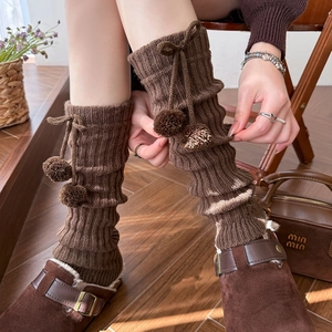 Detailed knit texture of dark brown leg warmers with drawstring pompom ties