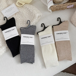 Flat lay of ribbed cotton crew socks in neutral tones with brand tags and cozy props