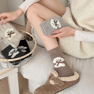 Detail of wool socks featuring plush puppy motifs and cute bow knots in earthy tones