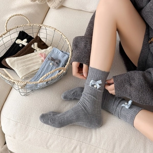 Detailed view of knitted wool socks featuring elegant bows and pearl embellishments