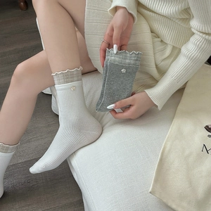 Close-up of cotton socks with ruffled edges and small floral accents in white and gray