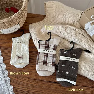 Detailed view of vintage knit socks with bow and floral patterns on wooden background