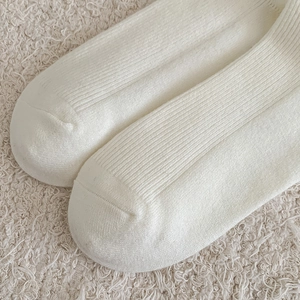 Close-up of white wool calf socks showing vertical ribbed texture and toe stitching details