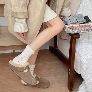 Close-up of stylish brown suede mule slippers with wool socks on warm white rug