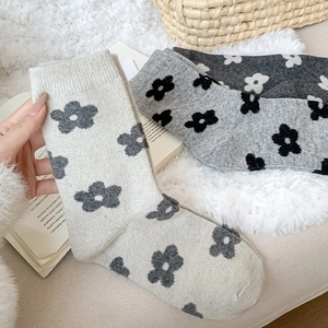 Detail of wool knit socks with floral patterns on a cozy white plush surface