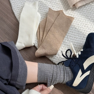 Detailed close-up of ribbed knit crew socks in white, khaki and grey textured cotton