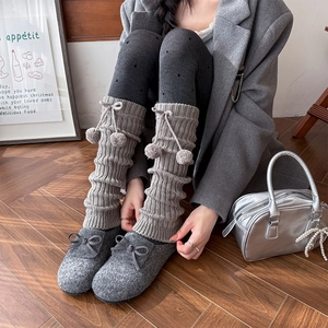 Gray knitted leg warmers with ribbons and fur balls for autumn winter styling