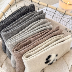 Close-up of five pairs of thick wool socks in warm tones inside a metal basket