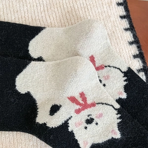 Detail of black knit cotton socks featuring a cute cartoon animal with red bow accent