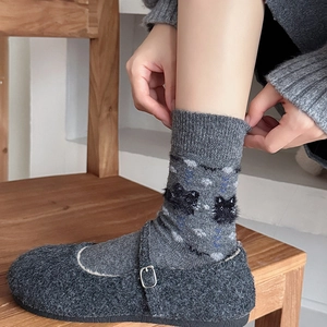 Detail of gray knitted mid-calf socks with fuzzy 3D cat pattern and Mary Jane flat shoes