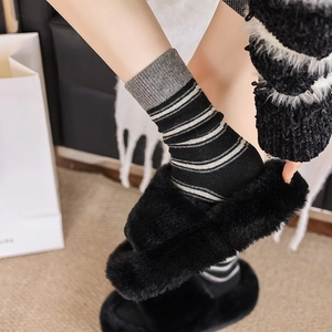 Gros plan de chaussettes en laine à rayures avec des pantoufles noires en peluche