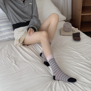 Detail of gray striped cotton socks with pink contrast cuffs in a cozy home setting