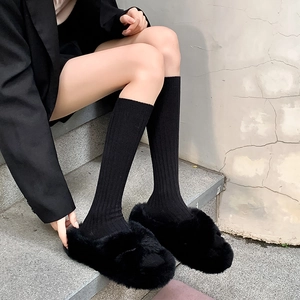 Minimalist black knit calf socks and fluffy faux fur slippers shown for winter wear