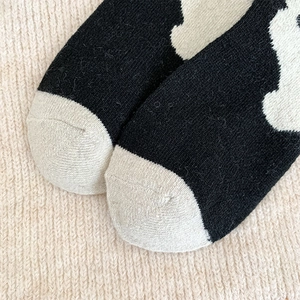 Close-up of thick knitted wool socks with black and white cow pattern and toe detail