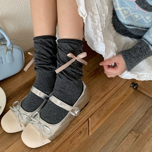 Detail of dark grey slouch socks with pink bows and silver Mary Jane shoes