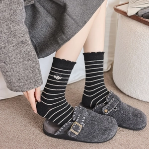 Détail de chaussettes rayées avec broderie chat et mules en feutre gris
