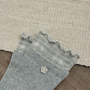 Close-up of knit cotton socks with ruffle cuffs and white floral button detail