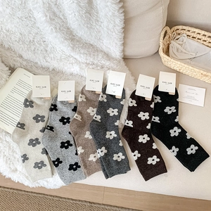 Set of 6 wool mid-tube socks in earth tones with floral prints on a white plush rug