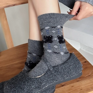 Close-up of thick knitted wool socks with black cat pattern and blue diamond lines