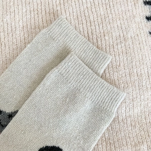 Close-up of ribbed cuffs and black polka dots on warm beige wool blend socks