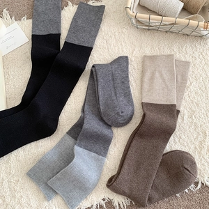 Close-up of ribbed knit texture on three pairs of color-block calf socks in warm tones