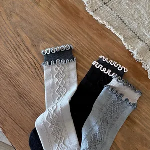 Detail of wool blend socks with vintage diamond pattern and ruffle cuffs on wood background
