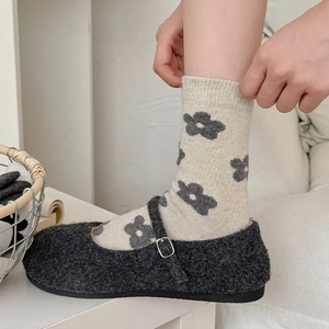 Close-up of cozy vintage floral wool socks with plush grey Mary Jane shoes