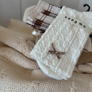 Detailed knit texture of floral socks with 3D bow and classic brown checkered pattern
