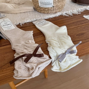 Detail of sweet ballet-style crew socks with ribbon bows in beige and cream colors