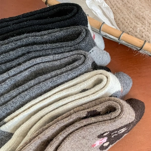 Detailed texture of thick wool socks in earth tones with cute cartoon embroidery detail