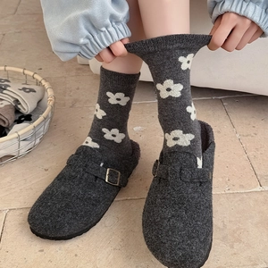 Close-up of vintage grey wool socks with white flower patterns and buckle shoes