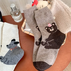 Close-up of thick knitted wool socks with cute cartoon bear and dog patterns in a basket