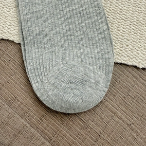 Macro shot of grey knitted socks showing detailed vertical ribbing and toe seam quality