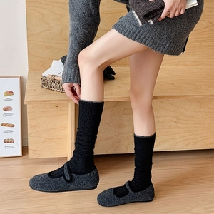 Close-up of wool Mary Jane flat shoes with black thick knitted socks on wooden stairs