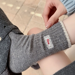 Détail de chaussettes en maille grise avec bordure en dentelle blanche et broderie Nice
