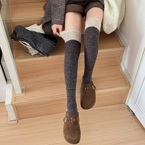 Nahaufnahme grauer Overknee-Socken mit beigem Strickbund und warmer Wollmischungstextur